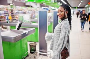 femme africaine posée en pull et jeans posés au supermarché contre le caissier. photo