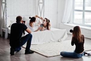 l'équipe de deux photographes prend des photos sur des jumelles en studio pendant qu'elles fabriquent leurs propres masques crème. photographe professionnel sur le travail.