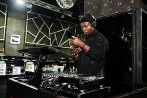 un dj afro-américain joue de la musique sur les platines de la discothèque. photo