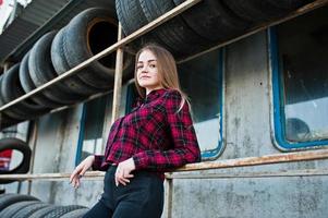 jeune fille hipster en chemise à carreaux dans la zone de montage des pneus. photo