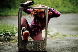 portrait de mode de fille sexy rousse en plein air. modèle séduisante femme dramatique avec une vieille boîte de télévision. photo