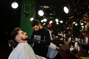 bel homme barbu au salon de coiffure, coiffeur au travail. photo