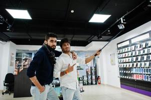 deux indiens mans client acheteur au téléphone mobile faisant selfie par bâton monopode. concept de peuples et de technologies d'asie du sud. magasin de téléphonie mobile. photo