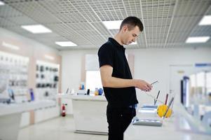 vendeur homme consultant professionnel en téléphonie mobile dans un magasin de technologie ou un magasin tenant un nouveau smartphone à portée de main. photo