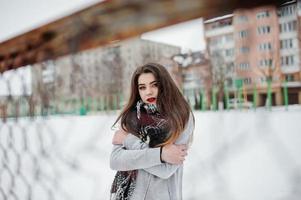 fille décontractée brune en écharpe en hiver dans la rue. photo