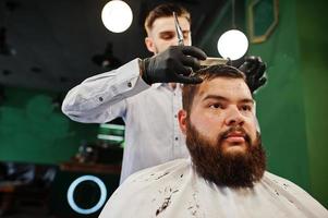 bel homme barbu au salon de coiffure, coiffeur au travail. photo