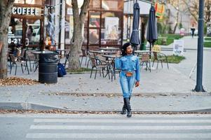 élégantes femmes afro-américaines à la mode en jeans et béret noir marchant sur la circulation piétonne. photo