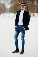 homme étudiant indien élégant en costume et lunettes posé à la journée d'hiver en plein air. photo