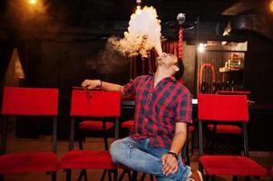 un homme asiatique fume du narguilé et se repose au bar-salon. photo