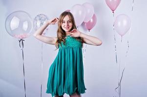 fille heureuse en robe turquoise verte avec des ballons colorés isolés sur blanc. célébrer le thème de l'anniversaire. photo