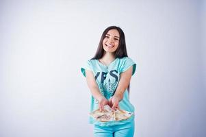 portrait d'une jolie fille en t-shirt et pantalon bleu ou turquoise posant avec beaucoup d'argent à la main. photo