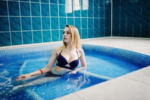 fille blonde sexy en maillot de bain bleu se reposer dans la piscine sauna. photo