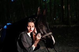 vêtements mystiques pour fille en noir avec cheval en bois. photo