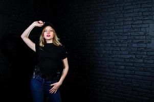 agent féminin du fbi en casquette et avec arme à feu au studio contre un mur de briques sombres. photo