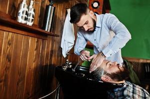 bel homme barbu au salon de coiffure, coiffeur au travail. tête de lavage. photo