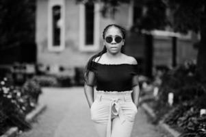 élégante femme afro-américaine à lunettes de soleil posées en plein air. photo