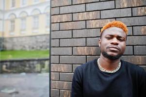 l'homme aux cheveux rouge africain porte une tenue noire posant à l'extérieur. photo