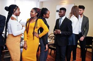 des hommes d'affaires multiraciaux se tenant au bureau et discutant ensemble. groupe diversifié d'employés en tenue de soirée. photo