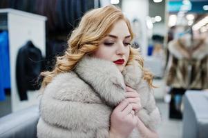 élégance fille blonde en manteau de fourrure au magasin de manteaux de fourrure et de vestes en cuir. photo