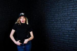 agent féminin du fbi en casquette et avec arme à feu au studio contre un mur de briques sombres. photo