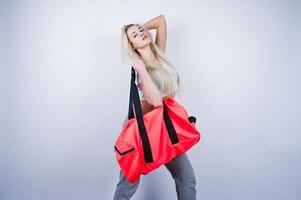 fille sportive blonde avec grand sac de sport posé au studio sur fond blanc. photo