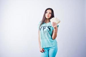 portrait d'une jolie fille en t-shirt et pantalon bleu ou turquoise posant avec beaucoup d'argent à la main. photo