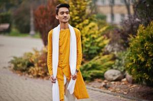 homme élégant indien en vêtements traditionnels jaunes avec foulard blanc posé à l'extérieur. photo