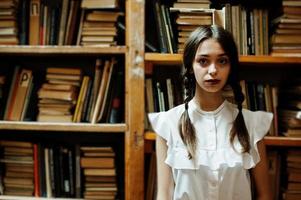 fille avec des nattes en blouse blanche à l'ancienne bibliothèque. photo