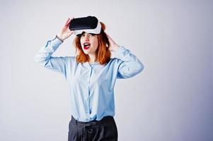 fille aux cheveux rouges en blouse bleue avec des lunettes vr au studio isolé sur blanc. photo