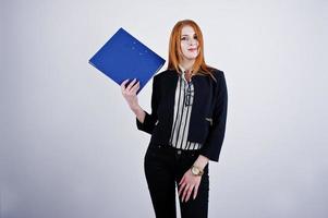 portrait d'une femme d'affaires rousse portant un chemisier rayé et une veste avec un dossier bleu. photo