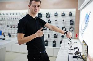 vendeur homme consultant professionnel en téléphonie mobile dans un magasin de technologie ou un magasin vérifier les nouvelles montres intelligentes. photo