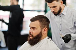 bel homme barbu au salon de coiffure, coiffeur au travail. photo