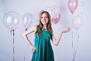 fille heureuse en robe turquoise verte avec des ballons colorés isolés sur blanc. célébrer le thème de l'anniversaire. photo