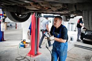 thème de la réparation et de l'entretien des voitures. mécanicien en uniforme travaillant dans le service automobile. photo