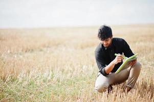 Agriculteur agronome sud-asiatique inspectant une ferme de champs de blé. notion de production agricole. photo