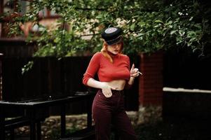 portrait de mode de fille sexy rousse en plein air. modèle attrayant séduction femme avec cigarette. photo