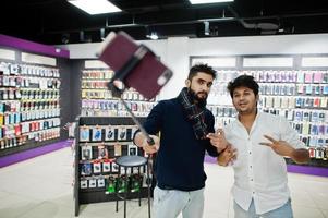 deux indiens mans client acheteur au téléphone mobile faisant selfie par bâton monopode. concept de peuples et de technologies d'asie du sud. magasin de téléphonie mobile. photo