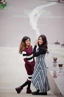 portrait de deux belles jeunes adolescentes indiennes ou sud-asiatiques en robe posées dans les escaliers de la ville. photo