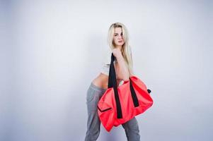 fille sportive blonde avec grand sac de sport posé au studio sur fond blanc. photo