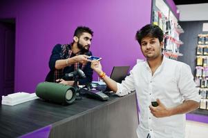 l'acheteur client indien paie son nouveau smartphone pour le vendeur par carte de crédit dans un magasin de téléphonie mobile. concept de peuples et de technologies d'asie du sud. magasin de téléphonie mobile. photo