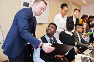 jeunes créatifs multiraciaux dans un bureau moderne. groupe de jeunes gens d'affaires travaillent avec un ordinateur portable, une tablette. équipe de pigistes à succès dans le coworking. photo