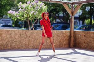 jolie et mince fille afro-américaine en robe rouge avec des dreadlocks en mouvement s'amusant dans la rue. modèle noir élégant. photo