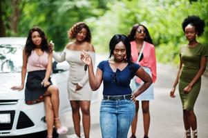 groupe de cinq filles afro-américaines heureuses posées contre la voiture, l'une d'elles montre les clés. photo