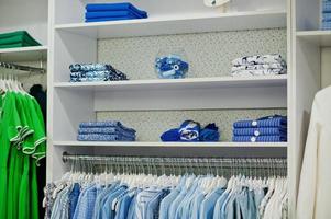 ensemble de vêtements colorés bleus féminins sur les étagères et les étagères de la toute nouvelle boutique moderne du magasin de vêtements. collections de robes printemps été. photo
