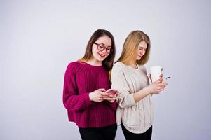 deux filles en robes violettes parlent ou envoient des SMS au téléphone dans le studio. photo