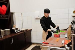 chef professionnel porter en noir faisant des sushis et des petits pains dans une cuisine de restaurant de cuisine traditionnelle japonaise. photo