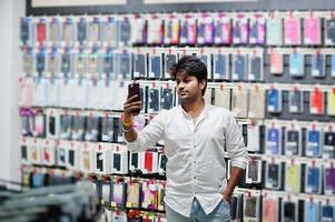 acheteur client indien dans un magasin de téléphonie mobile faisant du selfie sur son nouveau smartphone avec étui. concept de peuples et de technologies d'asie du sud. magasin de téléphonie mobile. photo