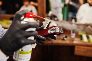 coiffeur nettoyant sa machine à raser les cheveux au salon de coiffure. photo