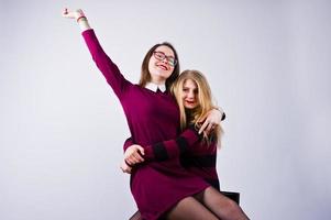 filles en robes violettes s'amusant et posant sur la chaise dans le studio. photo