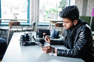 photographe de jeune homme asiatique intelligent travaillant avec une tablette pendant qu'il était assis au café. photo